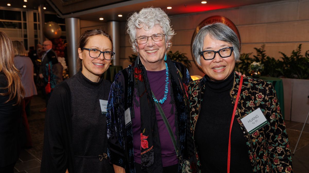 Three women smiling at the NESA reunion.