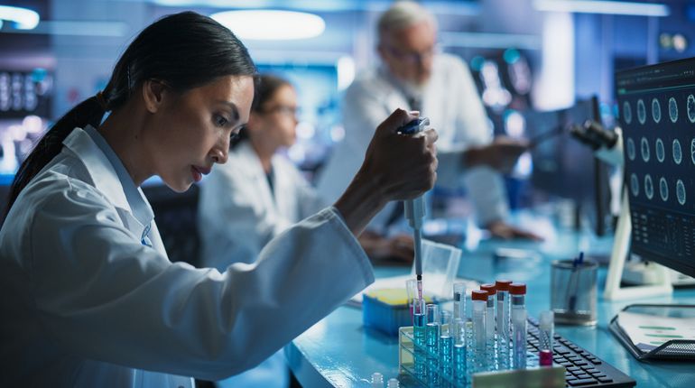 woman adding substance to a test tube