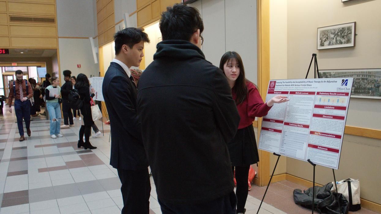 Female student explaining a poster to two male students. 