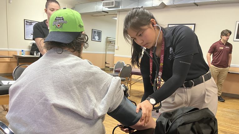 Woman takes man's blood pressure.