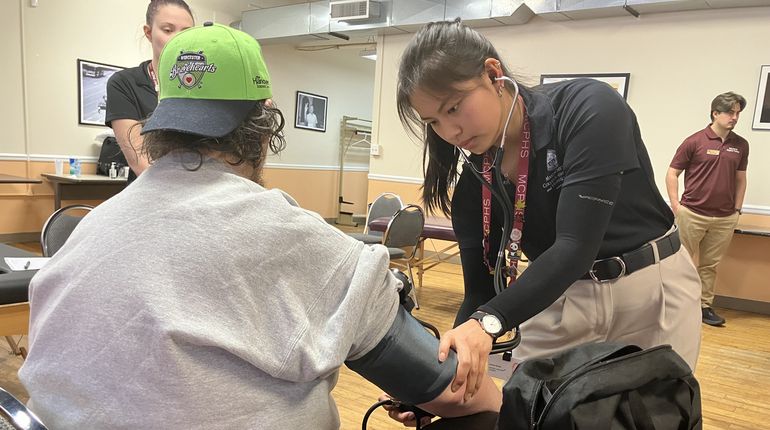 Woman takes man's blood pressure.