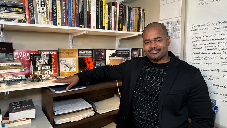 Mikal Gaines sits in front of a bookcase.