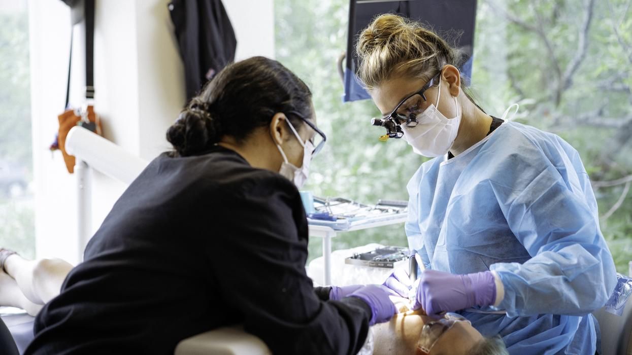 Two MCPHS dental hygiene students working on a patient in the Worcester Forsyth Dental Hygiene clinic. 