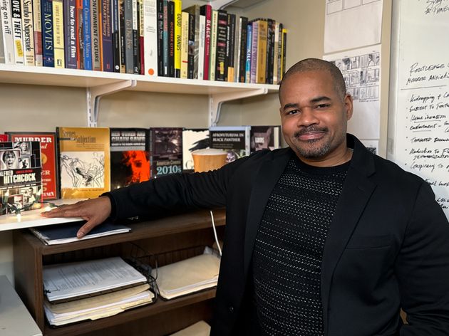 Mikal Gaines sits in front of a bookcase.
