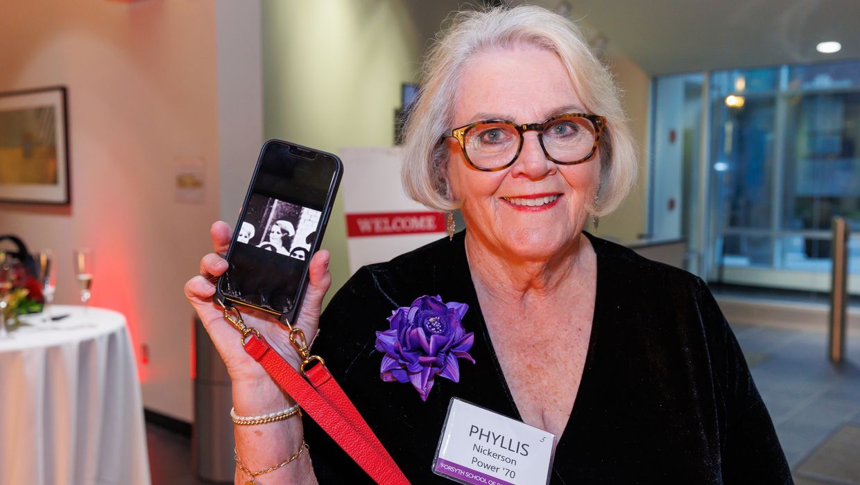 Golden Grad Reunion attendee holding up a phone. 