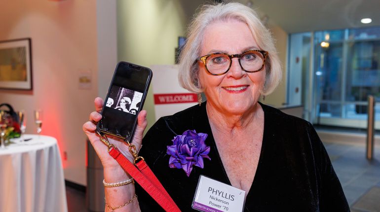 Golden Grad Reunion attendee holding up a phone. 