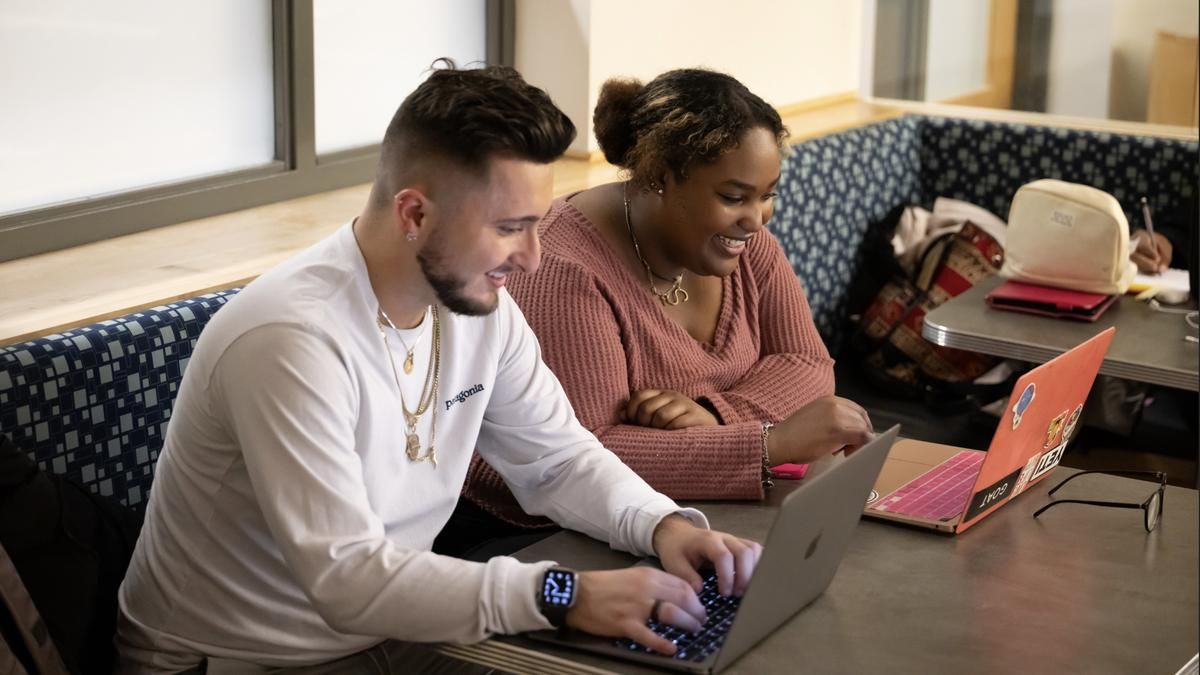 A man and a woman looking at their laptops.