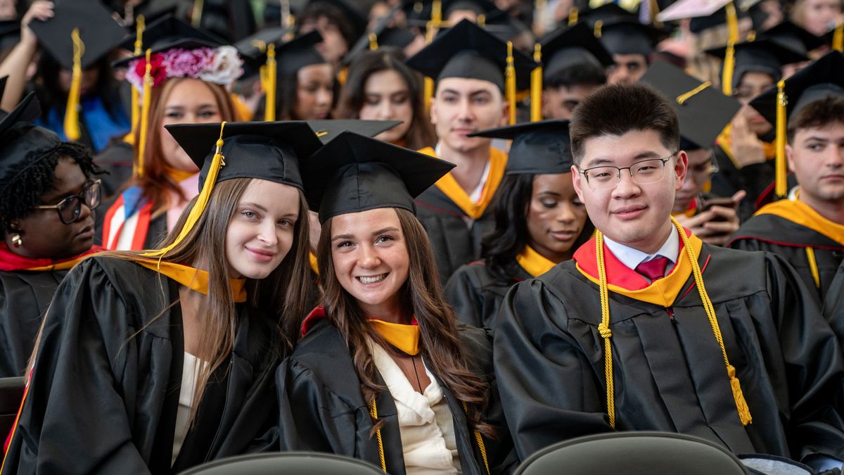 Close up of smiling students in cap and gowns. 