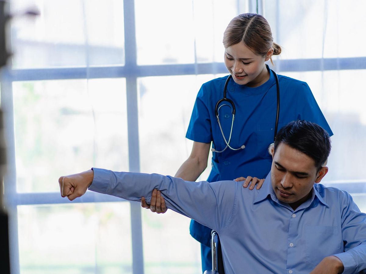 Nurse working with patient, lifting his arm and shoulder 