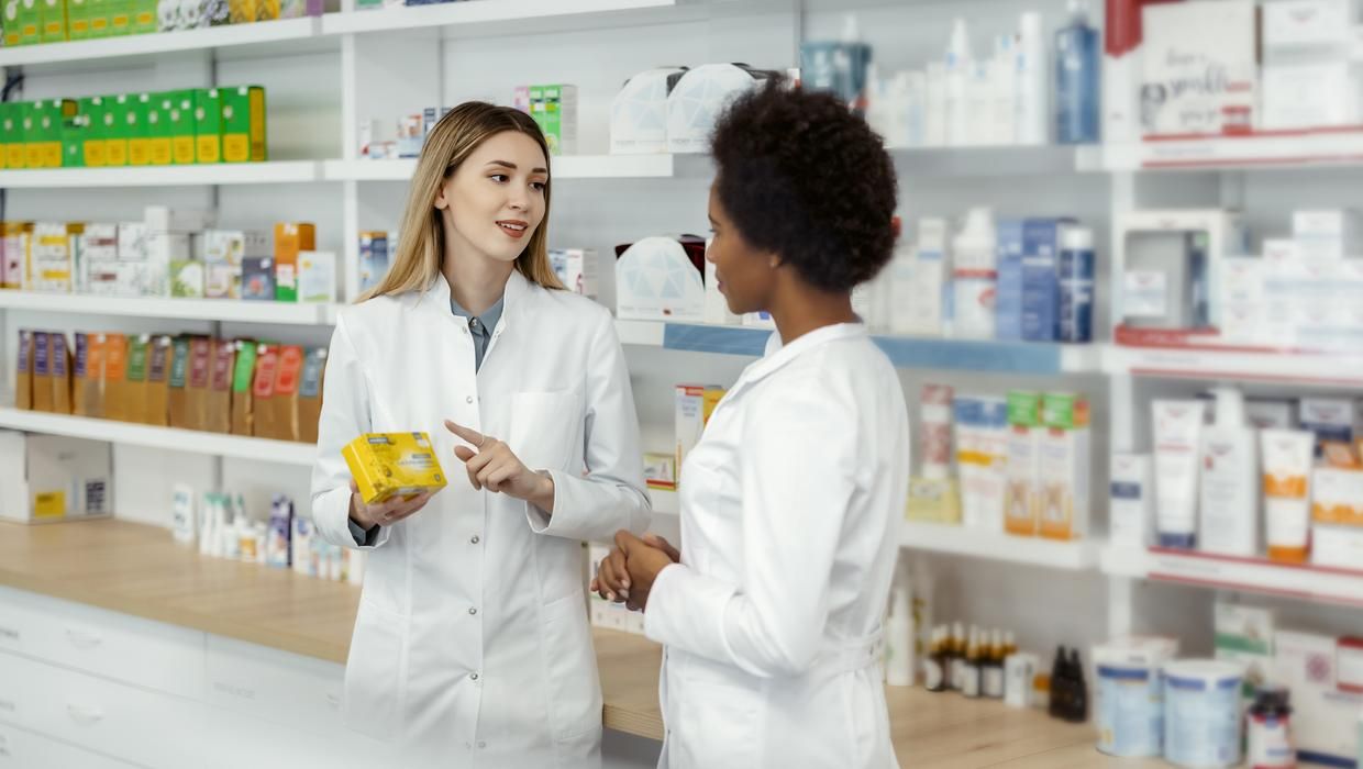Two female pharmacists talking in a pharmacy.