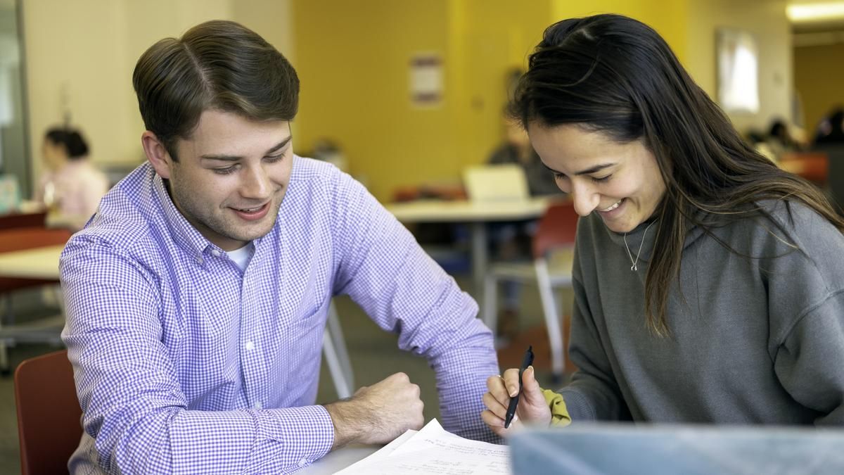 Male and female student studying in the library. 