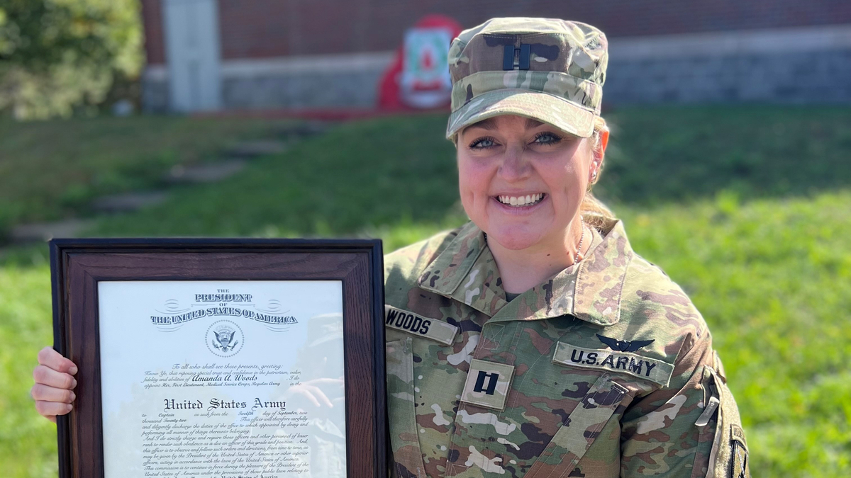 Captain Amanda Woods holds a framed certification from the President.