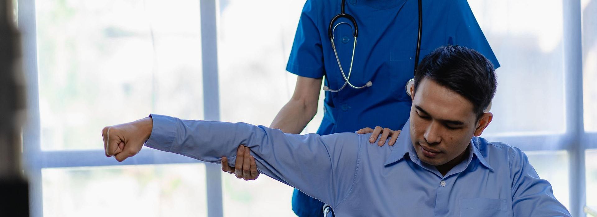 Nurse working with patient, lifting his arm and shoulder 