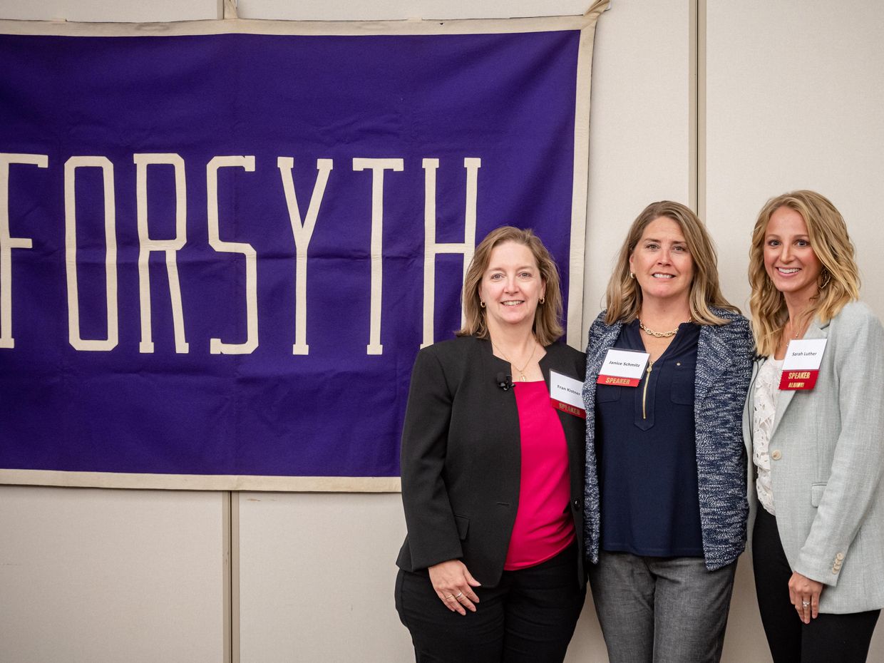 Alumni standing in front of Forsyth Banner.