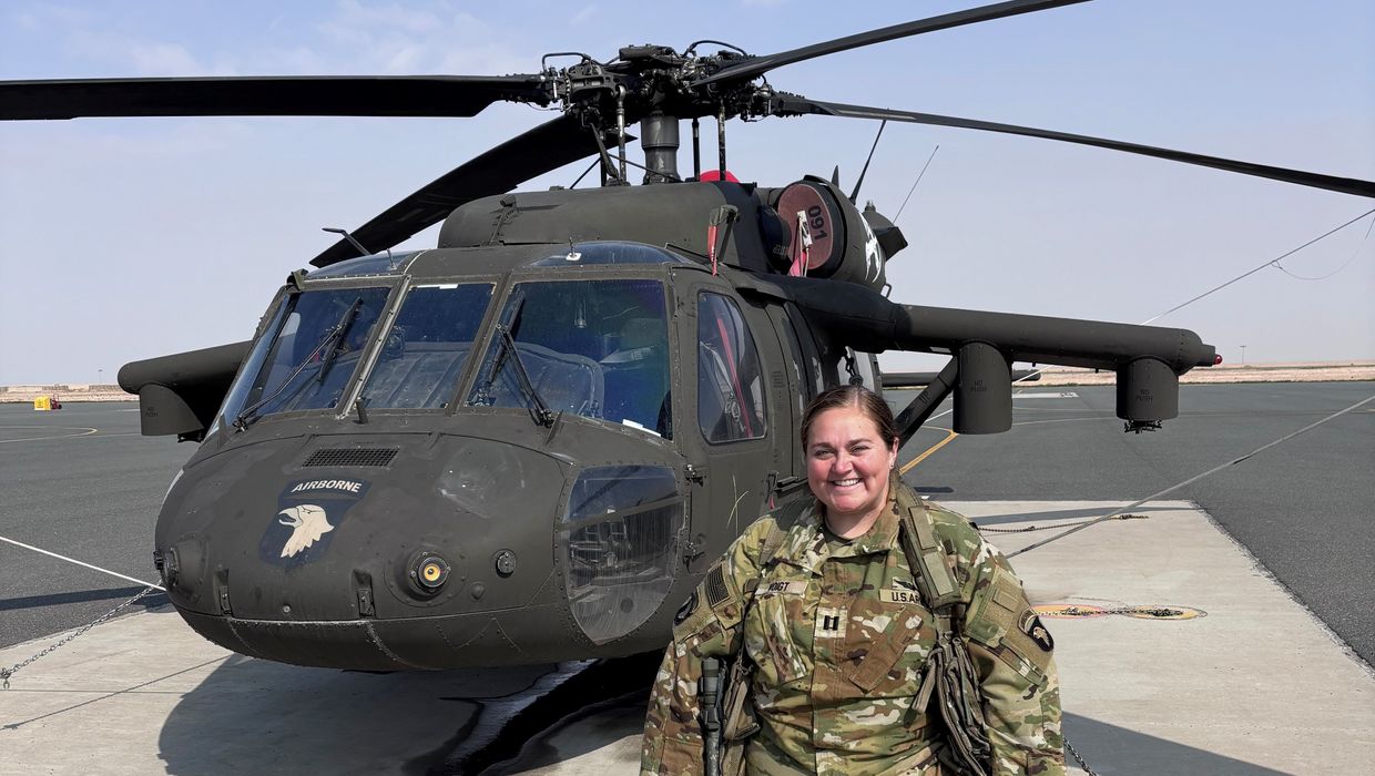 Captain Amanda Woods stands in front of helicopter.