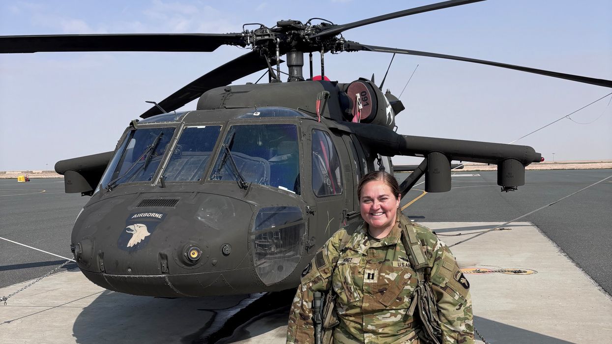 Captain Amanda Woods stands in front of helicopter.