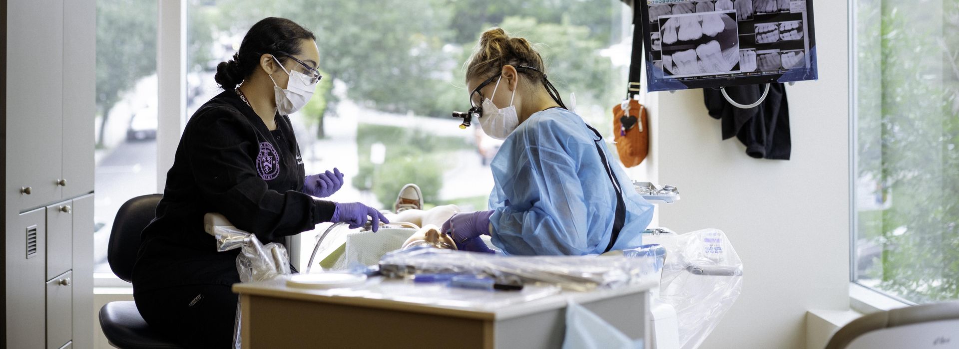 Two female dental hygiene students working on a patient. 
