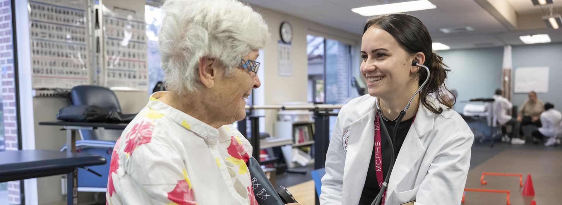 Physical Therapy student wearing a stethoscope working on an elderly client. 