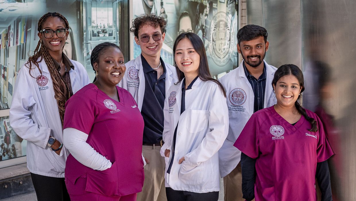 Smiling students in white coats and scrubs. 