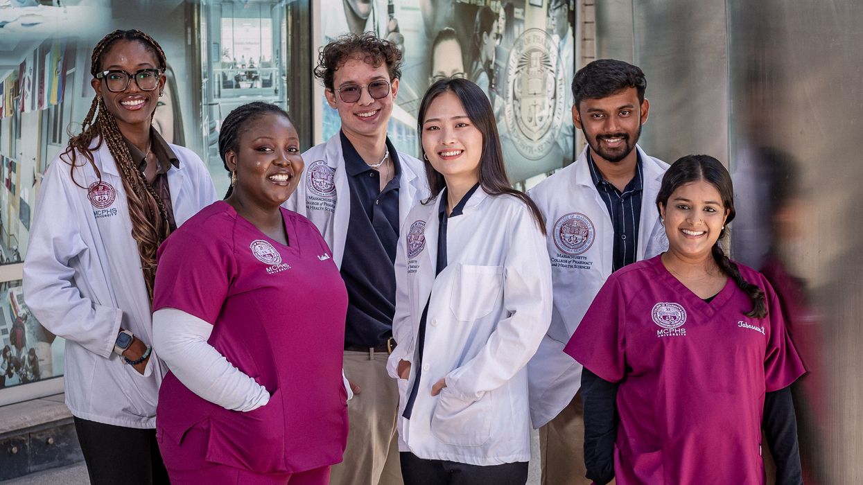 Smiling students in white coats and scrubs. 