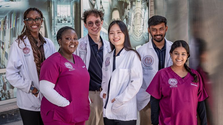 Smiling students in white coats and scrubs. 