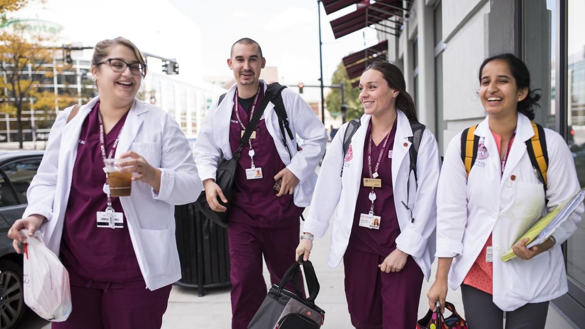 Group of laughing students in scrubs walking down the street. 