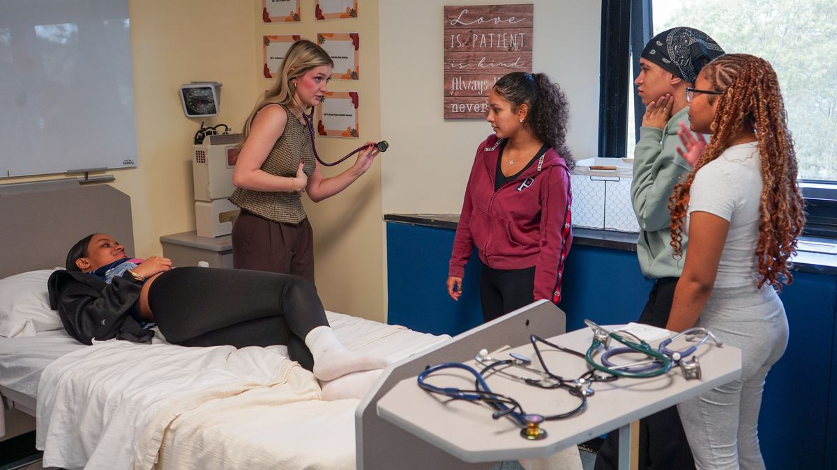 Kaitlyn McNaught shows students an alternative way to position a patient to listen to their heartbeat with a stethoscope.