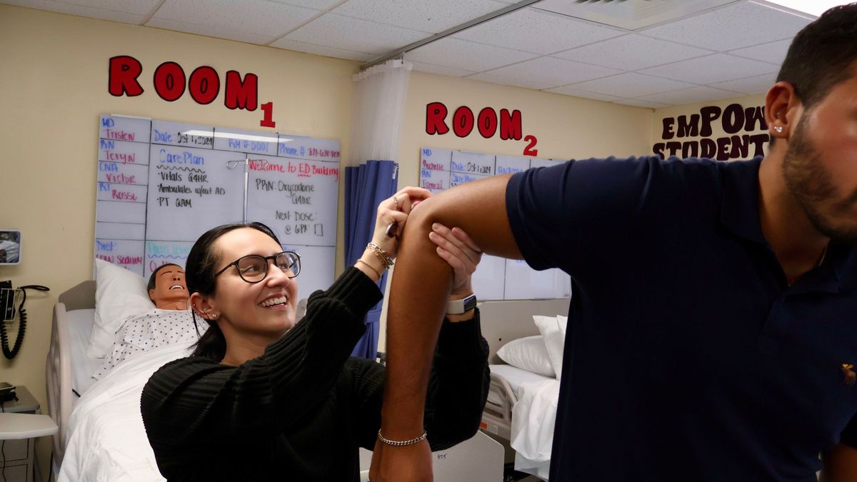 A woman holds a man's elbow.