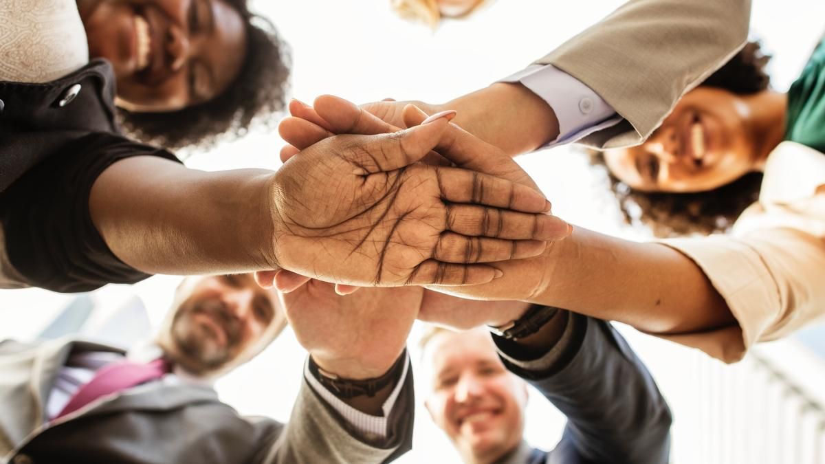 Group of people with hands on top of one another in a circle. 