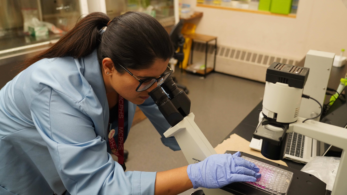 Ayushi Saxena looks into a microscope.