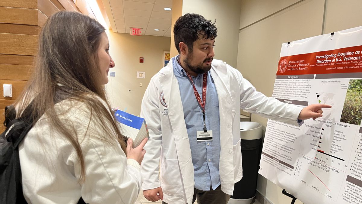 A man and woman look at a poster.