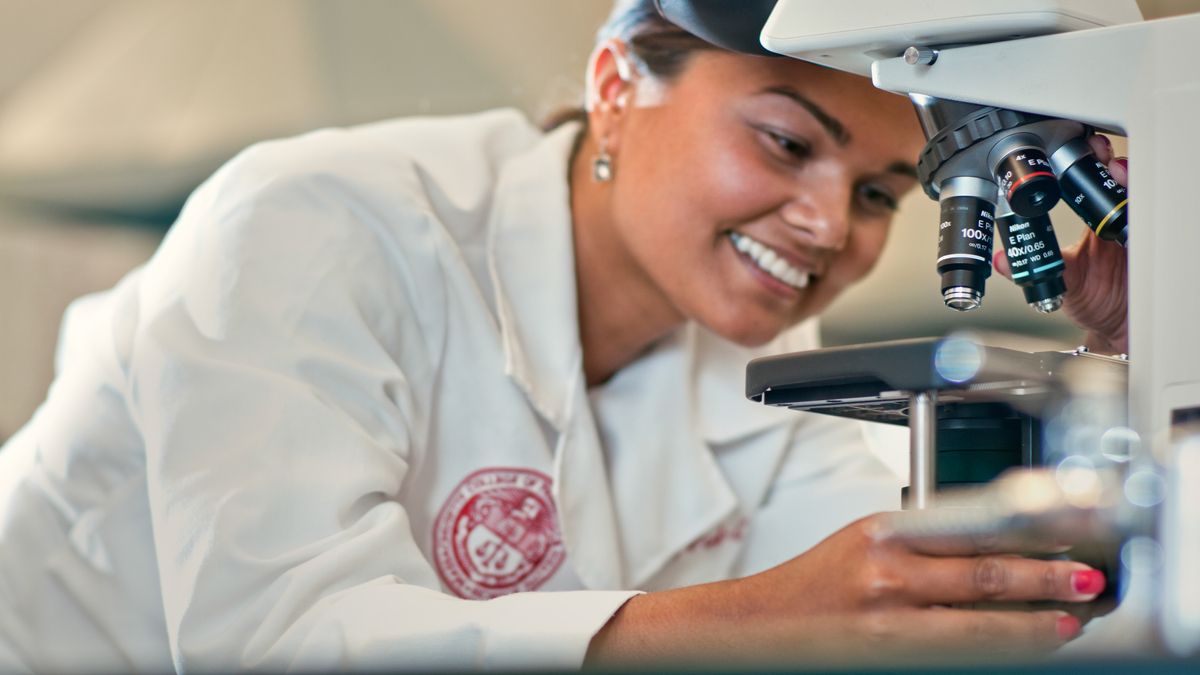 Female student using microscope.