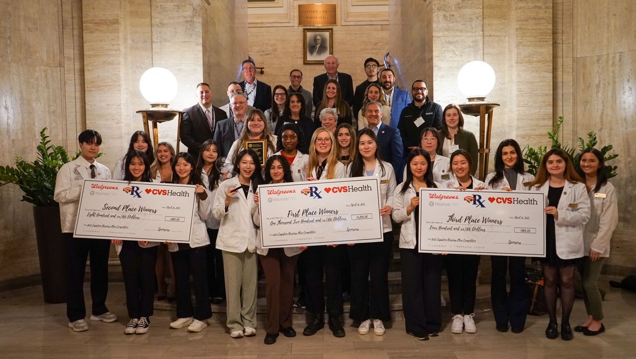 People holding large checks at the MCPHS Annual Capstone Business Plan Competition