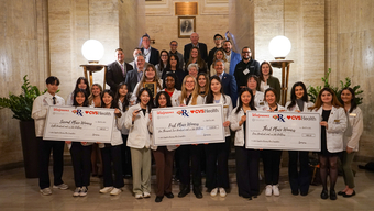 People holding large checks at the MCPHS Annual Capstone Business Plan Competition