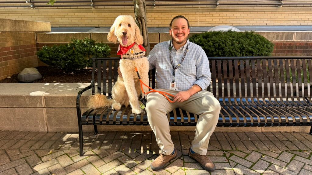 Henry Mallett pets MCPHS's therapy dog, Woodman.