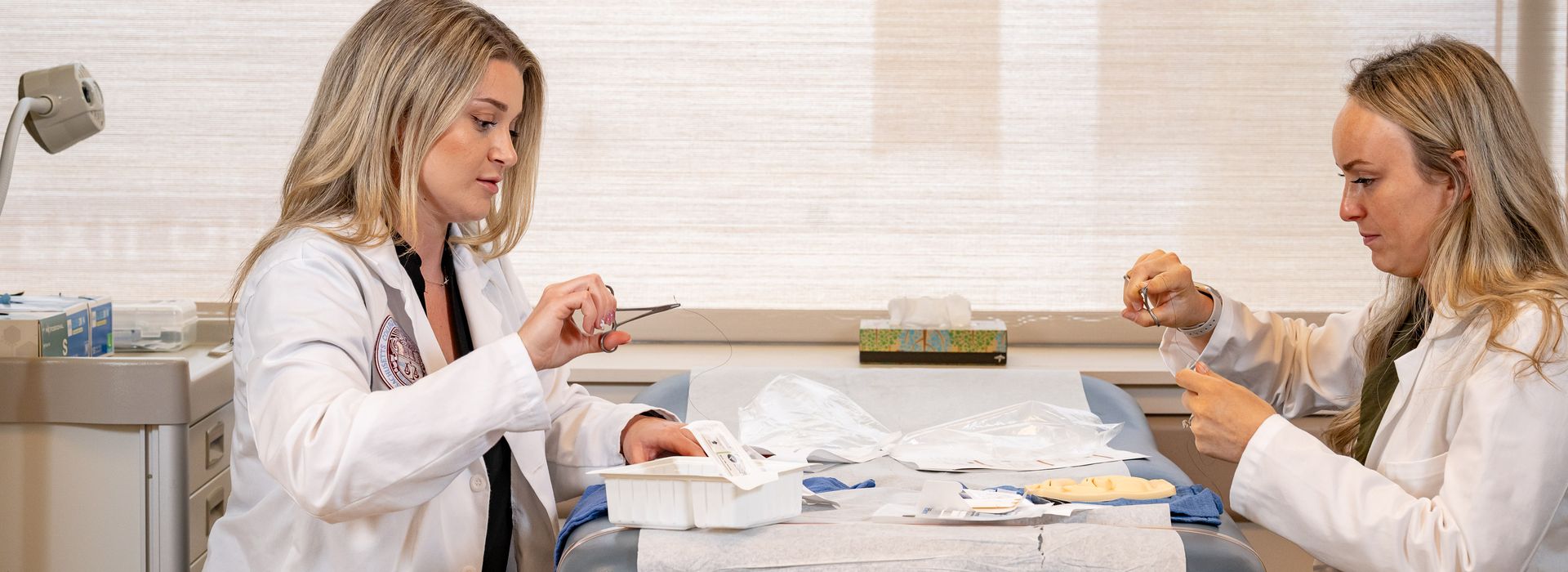 Two Graduate Nursing students practicing stitches.