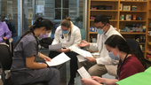 4 MCPHS students in a lab looking at papers.