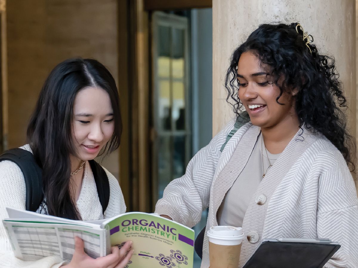 Two students looking at a textbook with the copy "12 More Gifts".