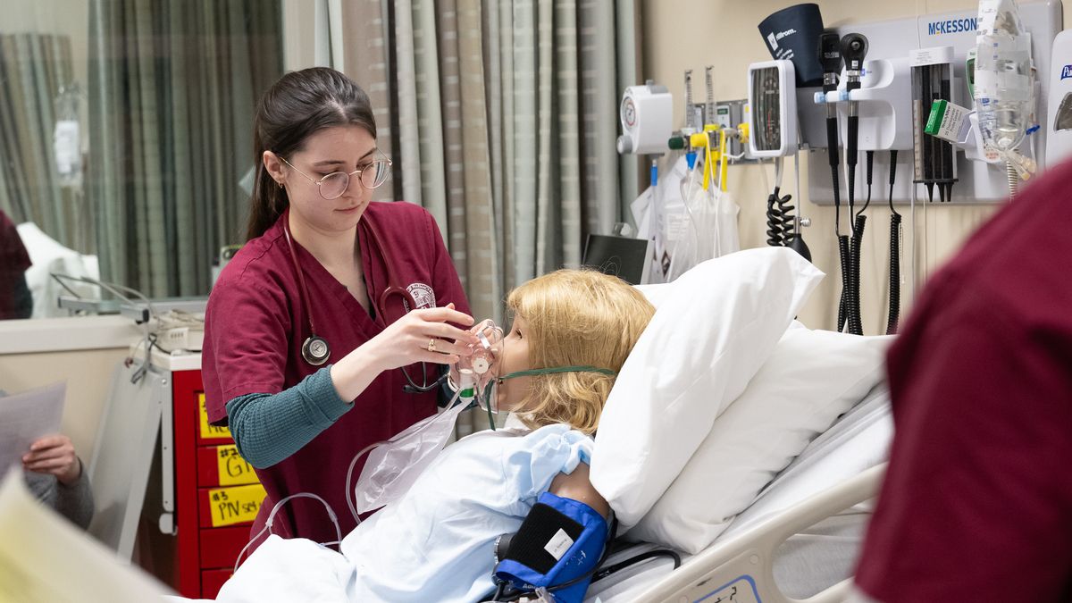 Nursing students working in group lab on the Boston campus, practicing on manikins.