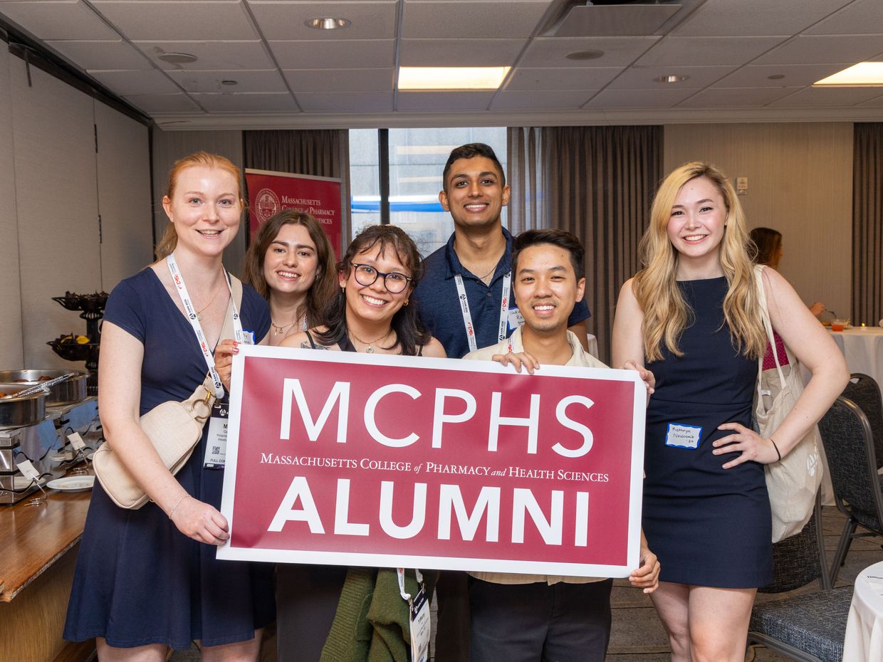 MCPHS Alumni holding a sign.