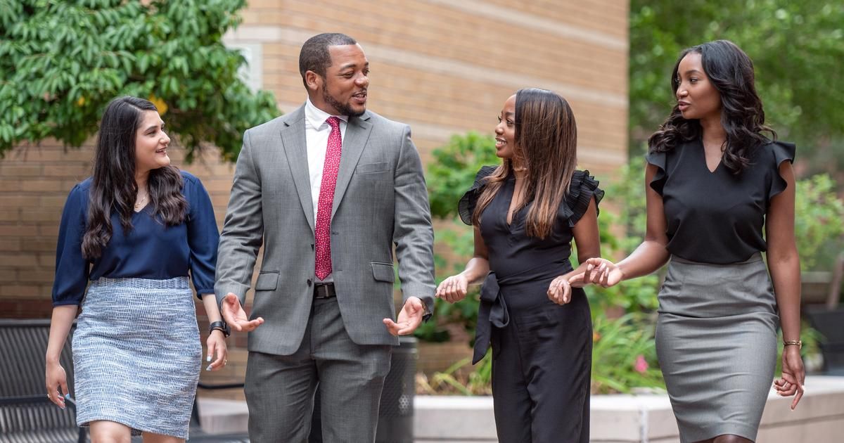 Students in professional dress walking down a street. 