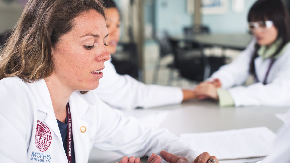 Female acupuncture student taking a patients pulse. 