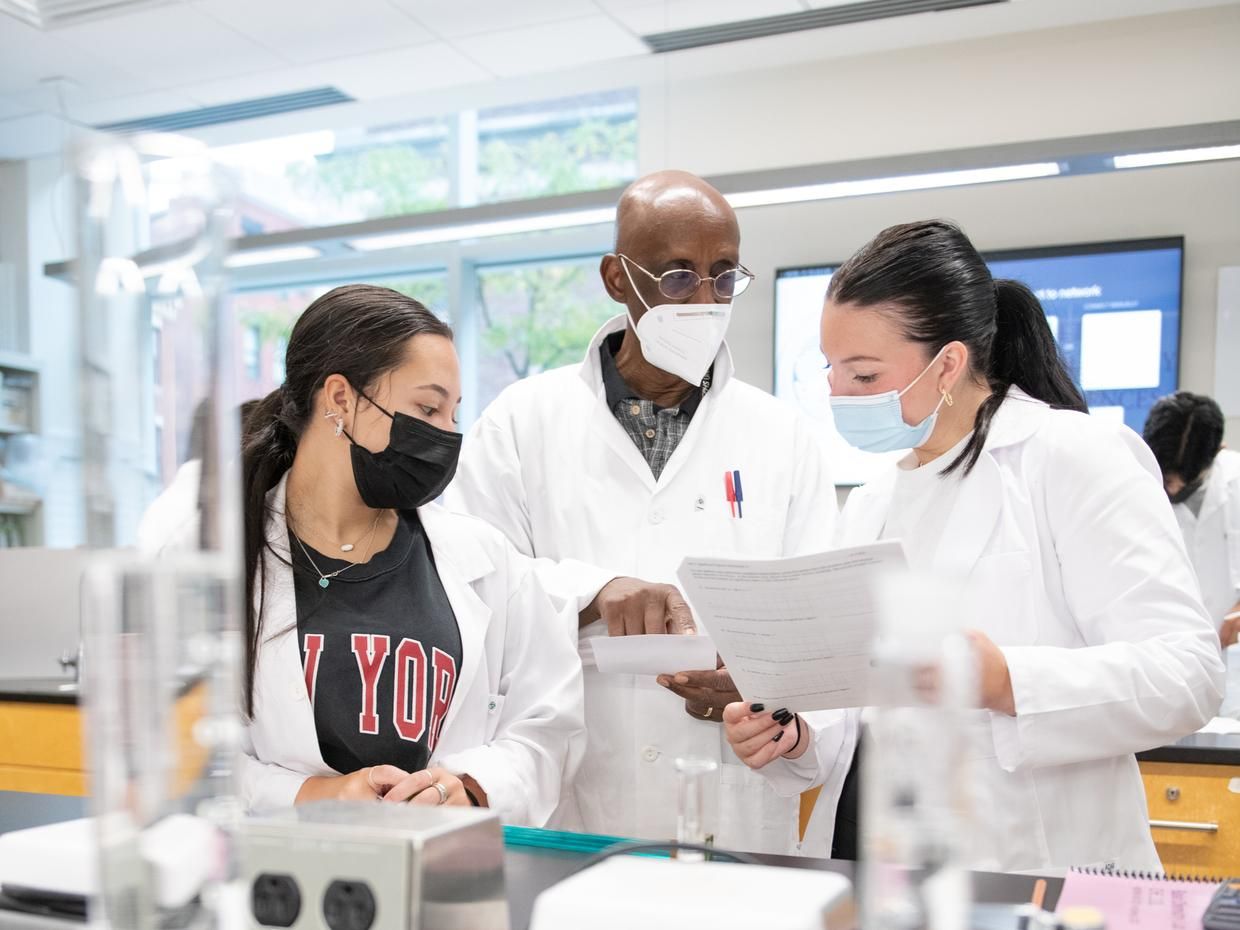 two students talking to a professor in a lab