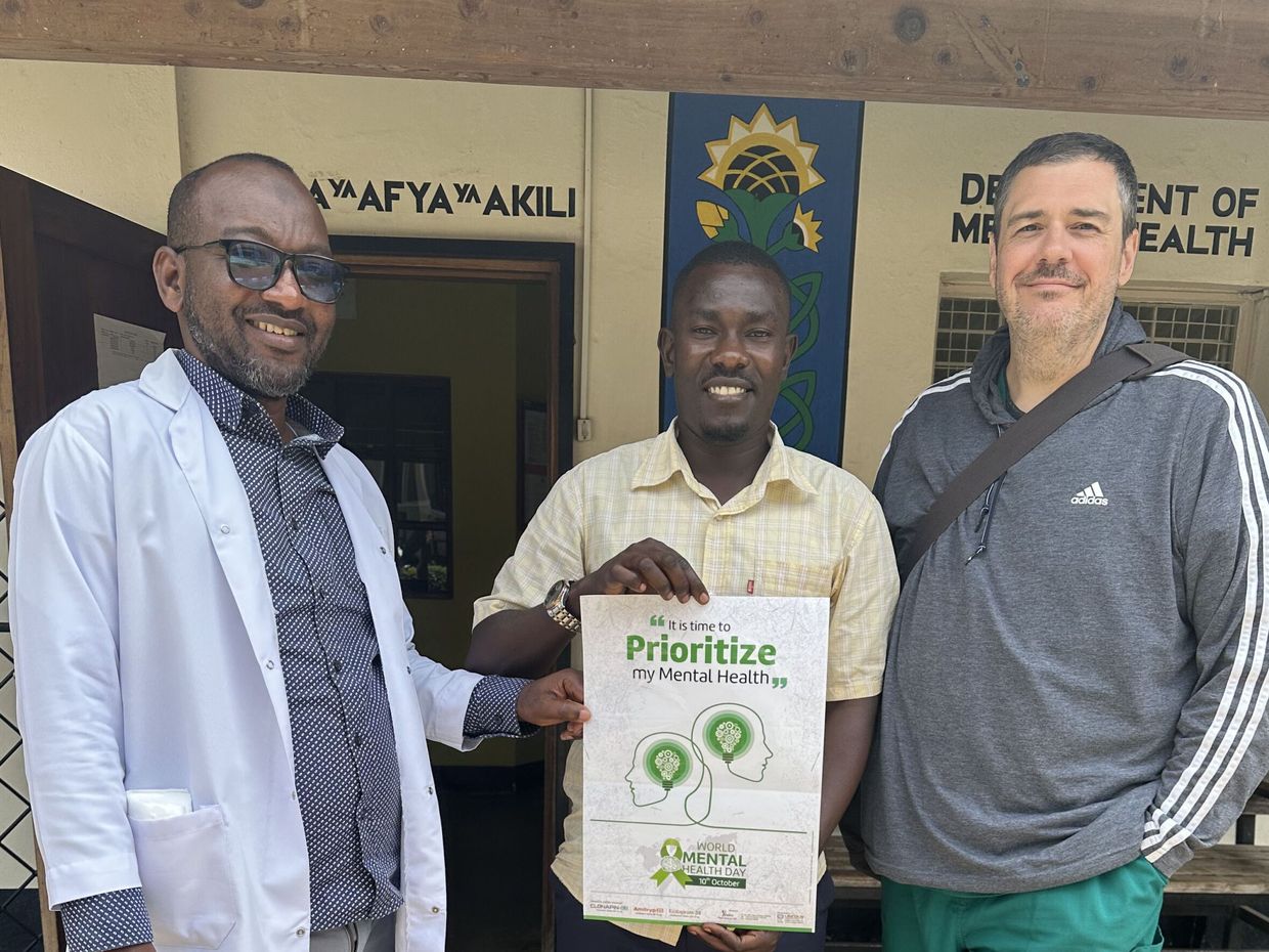 Dr. Trae Stewart stands next to two men in Guinea.