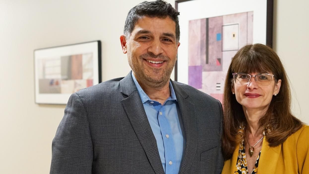 Kayhan Parsi, JD, PhD, HEC-C, and Nanette Elster, JD, MPH, pose together for a photo in a hallway