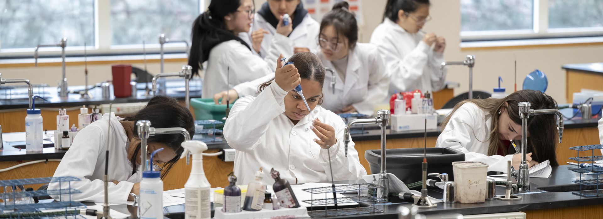 Student's working in big lab classroom, interacting with one another and the professors.