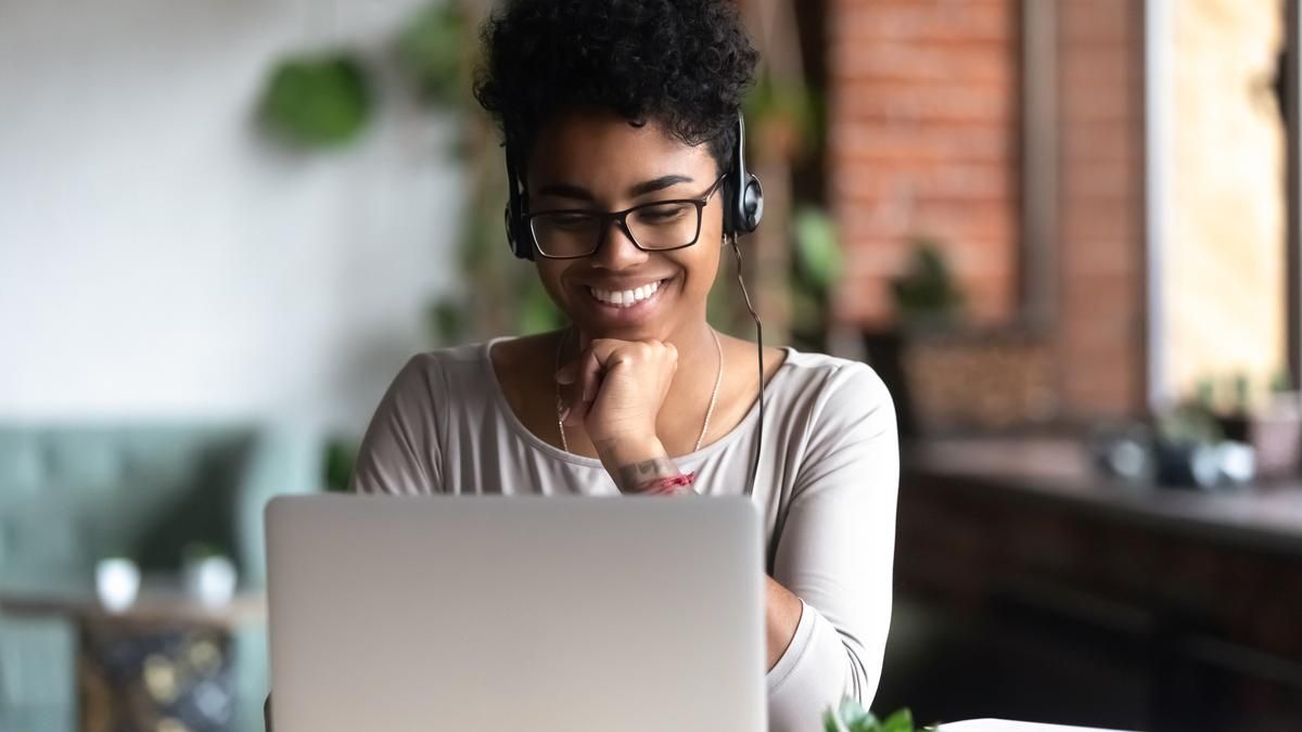 Woman in front of laptop with headphones. 