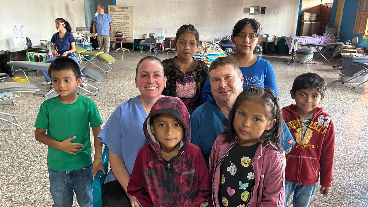 A man and a woman sit with children on a service trip to Guatemala. 