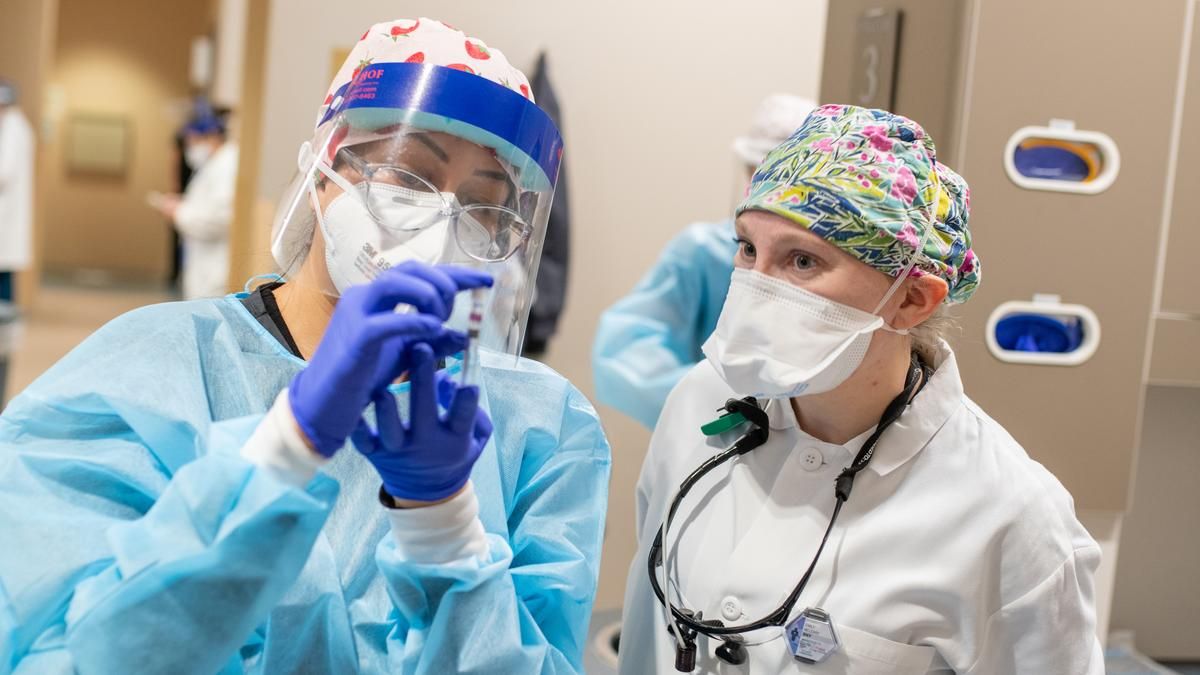 Dental Hygiene student and faculty looking at a syringe. 