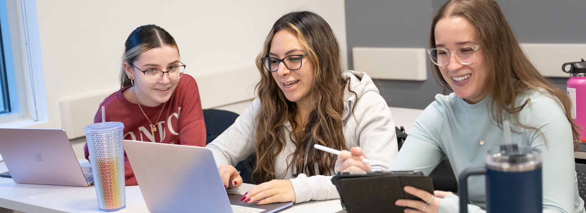 Three MCPHS students in front of their laptops. 